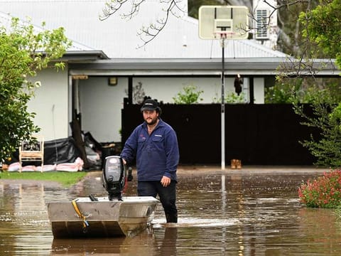 A man pushes a boat as floodwaters inundate a Victorian residential area amidst evacuation orders in Rochester, Australia, October 14, 2022.