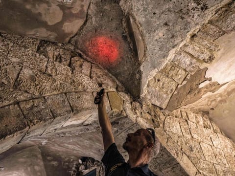 Shai Halevi, archaeologist of the Israel Antiquities Authority (IAA), illuminates a graffiti bearing the name of Adrian von Bubenberg, a Swiss knight who was military commander and mayor of Bern in the 15th century and who had undertaken a 1466 pilgrimage to Jerusalem, during their archaeological survey of a wall at the "King David Tomb Complex" on Mount Zion outside the old city walls of Jerusalem on October 20, 2022.