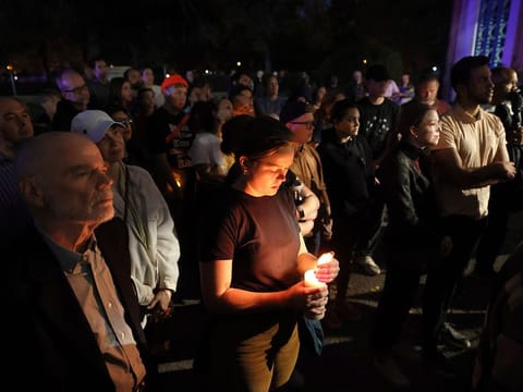 Marie Crane, center, holds a candle during a vigil in Tower Grove Park for the victims of a school shooting at Central Visual & Performing Arts High School in St. Louis on Monday, Oct. 24, 2022.