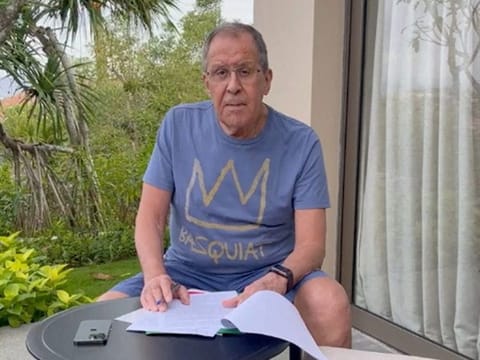 Russian Foreign Minister Sergei Lavrov reads documents on a patio in Bali on November 14, 2022, in this still image taken from video uploaded on the Telegram channel of Foreign Ministry Spokeswoman Maria Zakharova.