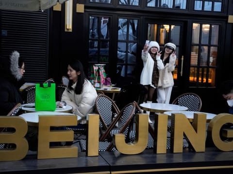 Residents pose for selfies outside a popular bakery in Beijing, Wednesday, Dec. 28, 2022. China says it will resume issuing passports for tourism in another big step away from anti-virus controls that isolated the country for almost three years, setting up a potential flood of Chinese going abroad for next month's Lunar New Year holiday. (AP Photo/Ng Han Guan)