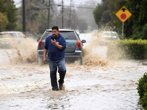 A resident walks along College Road after the area was flooded during a recent storm in Watsonville, California.