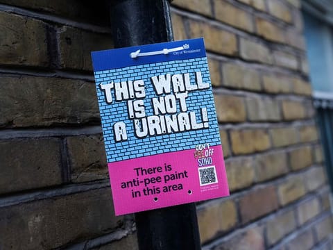 A board indicating that the walls of the area are covered by anti-pee paint in Soho.