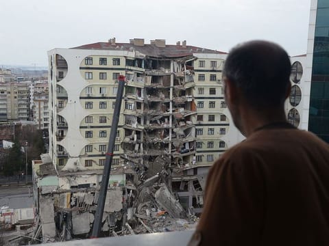 A man looks on at search and rescue operations conducted in the rubble of a collasped building in Diyarbakir.