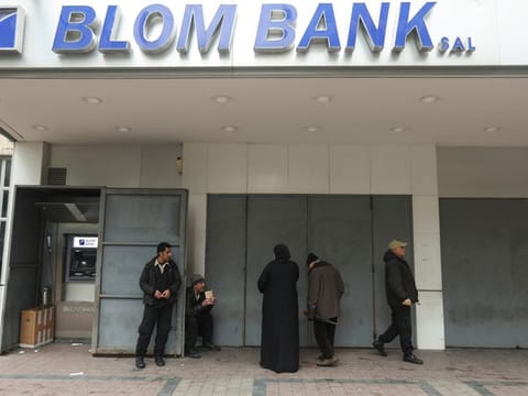 People stand at a closed branch of Blom Bank in Sidon, Lebanon, on February 7, 2023.