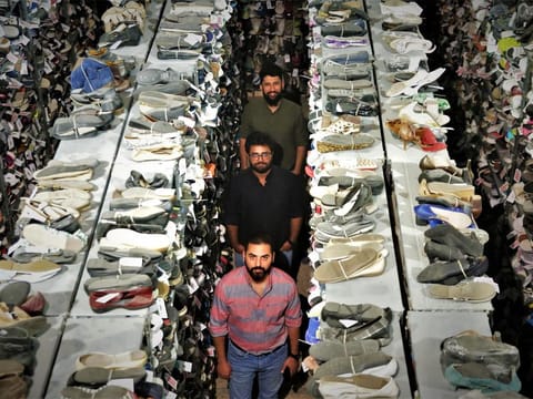 The three co-founders in the Swag Kicks warehouse with thousands of high-quality, branded sneakers around them.
