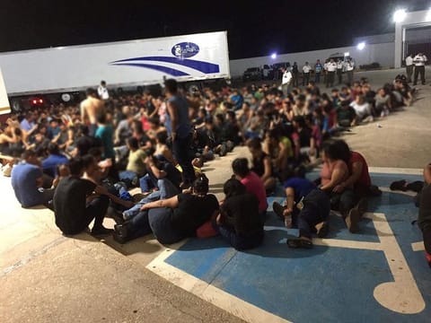 Migrants are pictured outside an abandoned truck trailer where Mexican authorities found migrants from Central America