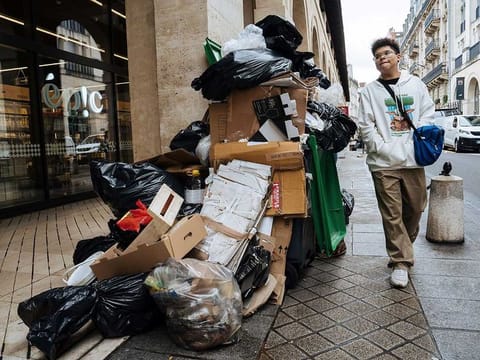 A man walks past uncollected garbage in Paris, Monday, March 13, 2023.