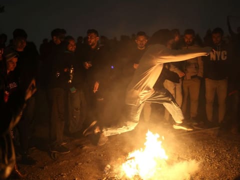 An Iranian woman jumps over a fire during the Wednesday Fire celebration (Chaharshanbeh Suri in Persian) at a park in Tehran, Iran March 14, 2023.