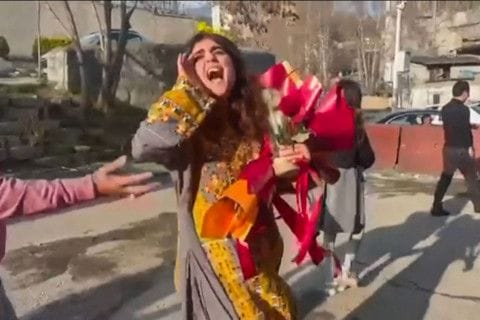 This image grab from a UGC video posted outside of Iran on March 15, 2023, shows Iranian activist and journalist Sepideh Gholian walking with a bouquet of flowers outside the walls of Evin prison in Tehran, following her release.
