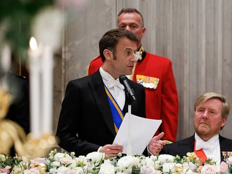 French President Emmanuel Macron (C) delivers a speech next to King Willem-Alexander of the Netherlands during a state dinner at the Royal Palace in Amsterdam, as part of a state visit to the Netherlands, on April 11, 2023.