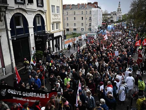 Protesters hold placards, including one reading "general strike, combat union" with the logo of the Unionists of the National Convention of Workers (CNT) trade union (L) during a demonstration on the 12th day of action after the government pushed a pensions reform through parliament without a vote, using the article 49.3 of the constitution, in Nantes, western France on April 13, 2023.