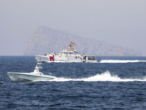 A US Navy L3 Harris Arabian Fox MAST-13 drone boat and the Coast Guard cutter USCGC John Scheuerman transit the Strait of Hormuz on Wednesday, April 19, 2023.