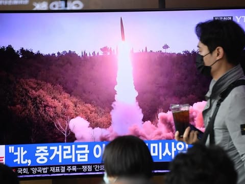 A man walks past a television screen showing a news broadcast with file footage of a North Korean missile test, at a railway station in Seoul on April 13, 2023.