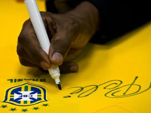 In this file photo taken on June 10, 2013, Brazilian football legend Pele, signs a national team shirt during a press conference at Volkswagen plant in Sao Bernardo do Campo, in Sao Paulo. On April 26, 2023, "pele" was added to the more than 167,000 words in the Michaelis Portuguese dictionary printed in Brazil.