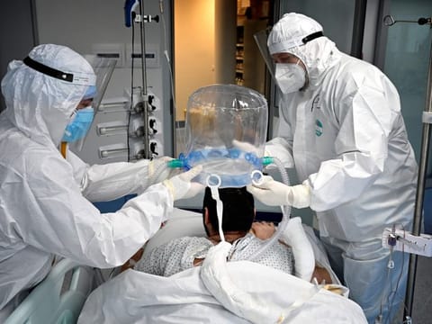 In this file photograph taken on December 30, 2021, medics help a patient to wear a new non-invasive technology that can reduce the need of intubation at COVID-19 intensive care unit (ICU) at The Institute of Clinical Cardiology (ICC) in Rome.