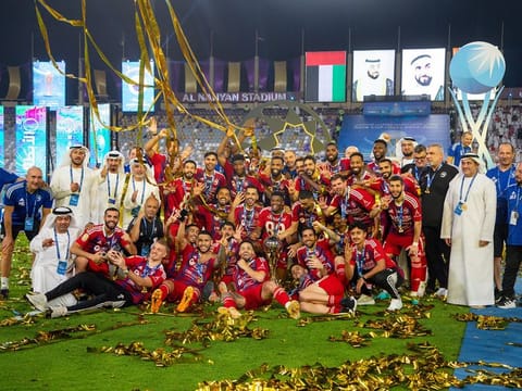 Sharjah players celebrate with the trophy after winning the final at Al Nahyan Stadium.