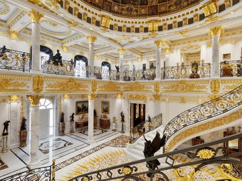 The entrance hall has grand staircases and a dome with handmade glass.