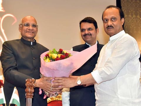 Maharashtra Governor Ramesh Bais congratulates the newly sworn-in State Deputy Chief Minister Ajit Pawar during a ceremony, as State Deputy CM Devendra Fadnavis looks on, at Raj Bhavan, in Mumbai on Sunday, July 2, 2023.