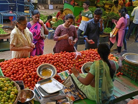 Customers buy tomatoes at a vegetable market in Hyderabad.