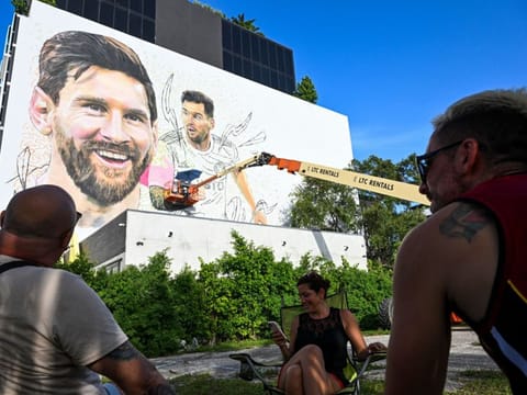 People watch as Argentine artist Maximiliano Bagnasco paints a mural of Lionel Messi in Wynwood, Miamis art district, in Miami, Florida on July 10.