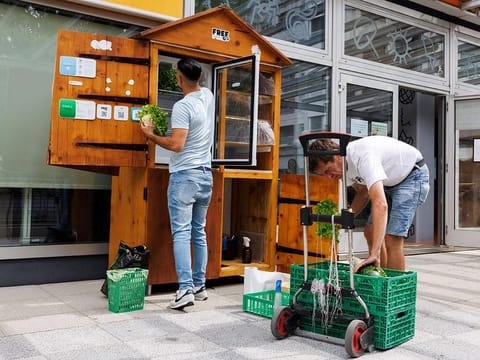 William, left, employee at association Eco-Citoyen, and Larry, volunteer at association Eco-Citoyen, refill with food a public refrigerator of project Free Go of the association Eco-Citoyen where people can give and take food that might otherwise perish, in Geneva, Switzerland