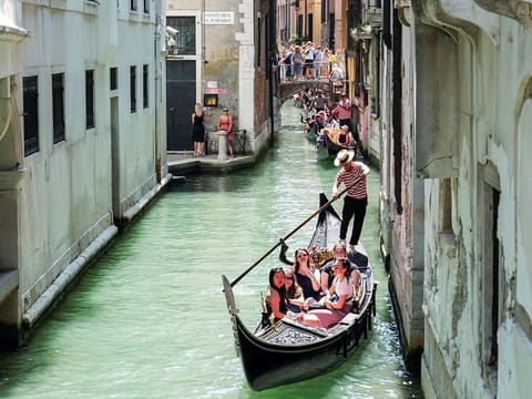 Gondoliers row their gondolas through the Venice Canal.