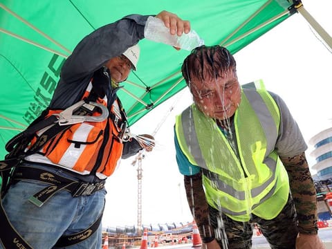 A worker pours cold water in a plastic bottle on his colleague in order to cool off him at a construction site in Incheon, South Korea.