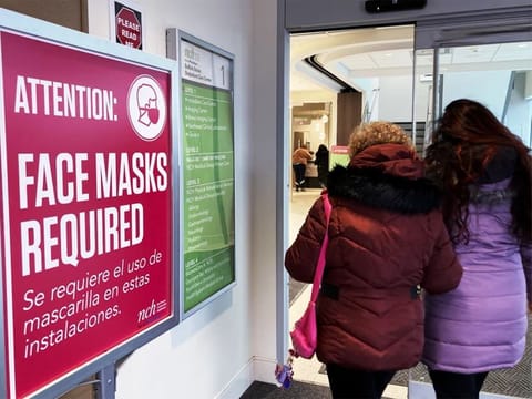 A sign announcing a face mask requirement is displayed at a hospital in Buffalo Grove, Illinois. COVID-19 hospital admissions are inching upward in the United States since early July 2023. It’s a small-scale echo of the three previous summers.