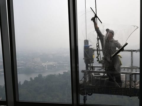 Surrounded by hazy conditions, a window washer cleans a window at the View of DC observation deck on June 8 in Arlington, Virginia. Smoke from wildfires in Canada have darkened the skies and affected the air quality in parts of the United States.