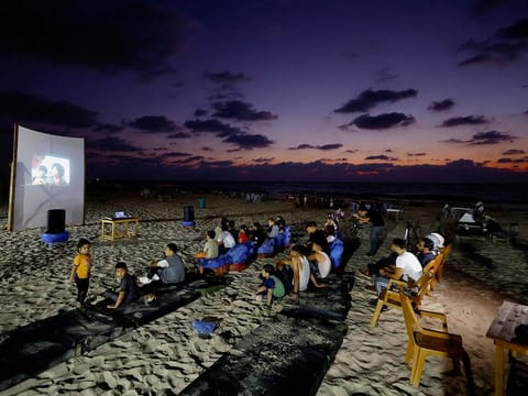 Palestinian families watch a large projector screen at a beachfront cafe during a rare cinema event, in Gaza City.