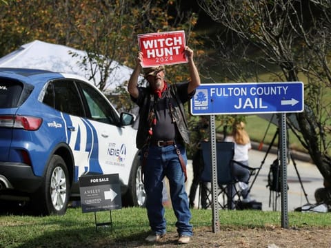 A man, calling himself "hat man", stands near the entrance to Fulton County Jail, as former US President Donald Trump is expected to turn himself in to be processed after his Georgia indictment, in Atlanta, on August 24, 2023.