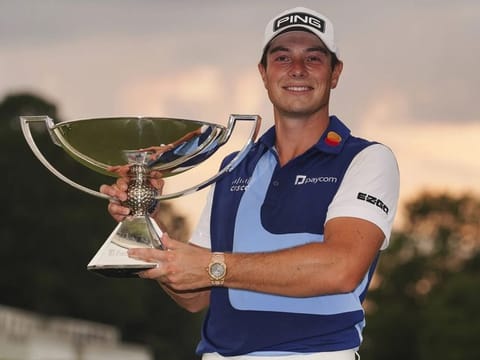 Viktor Hovland, of Norway, celebrates winning the Tour Championship golf tournament with the FedEx Cup trophy on the 18th green, Sunday, Aug 27, 2023, in Atlanta