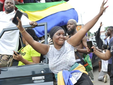Residents gesture and hold a Gabon national flag as they celebrate in Libreville on August 30, 2023 after a group of Gabonese military officers appeared on television announcing they were "putting an end to the current regime" and scrapping official election results that had handed another term to veteran President Ali Bongo Ondimba.