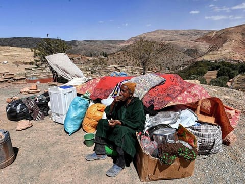 A man sits by salvaged items in the aftermath of the deadly 6.8-magnitude September 8 earthquake in the village of Ighermane near Adassil in central Morocco