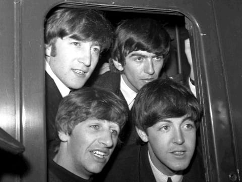 File photo: The Beatles, clockwise from top-left, John Lennon, George Harrison, Paul McCartney and Ringo Starr, pose in a carriage window of train before they left Paddington Station in London, March 2, 1964.