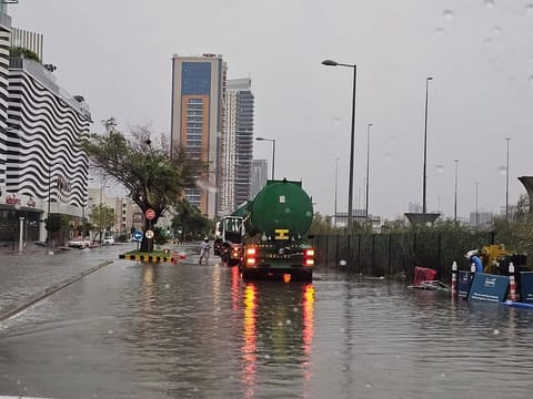 Workers use a tanker trump to pump rainwater from a Dubai road.