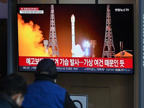 People watch a television screen showing a news broadcast with a picture of North Korea's latest satellite-carrying rocket launch, at a railway station in Seoul on November 22, 2023.