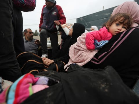 A woman holding a girl sits in a trailer as Palestinians fleeing north Gaza move southward during a temporary truce between Israel and Hamas, near Gaza City, on November 27, 2023.