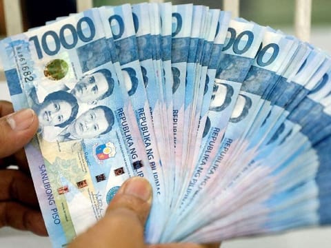 A worker shows Philippine peso bills inside a money changer in metro Manila, Philippines. File photo taken on August 14, 2017.