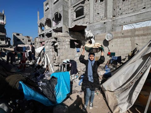 A woman carries bread next to destroyed houses in Rafah on the southern Gaza Strip on December 11, 2023, amid continuing battles between Israel and the militant group Hamas.