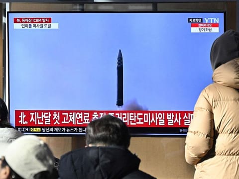 People watch a television screen showing a news broadcast with file footage of a North Korean missile test, at a railway station in Seoul.