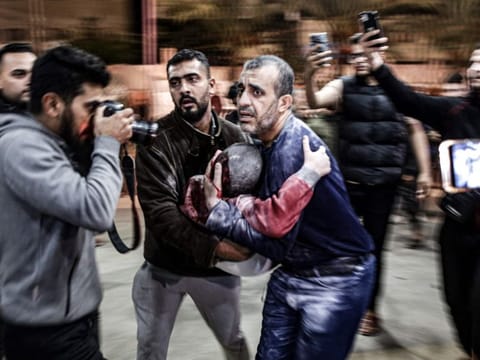 A man carrying a child, injured in Israeli bombardment, arrives at Nasser Hospital in Khan Younis in the southern Gaza Strip on December 17, 2023.