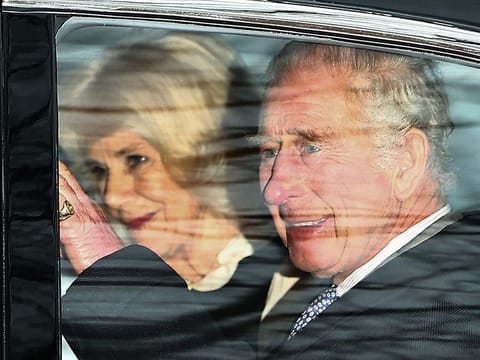 King Charles III and Queen Camilla wave as they leave by car from Clarence House in London on February 6, 2024.