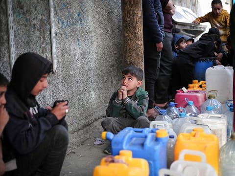 Palestinian children gather around containers of water in Rafah in the southern Gaza Strip on March 1, 2024, amid ongoing battles between Israel and the Palestinian Hamas movement.