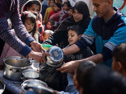 Palestinian children wait to receive food cooked by a charity kitchen amid shortages of food supplies, as the ongoing conflict between Israel and the Palestinian Islamist group Hamas continues, in Rafah, in the southern Gaza Strip, March 5, 2024.