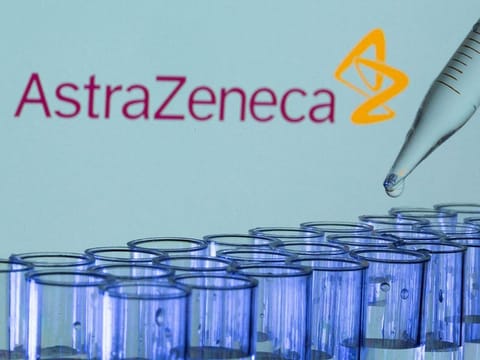 Test tubes are seen in front of a displayed AstraZeneca logo.