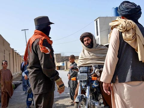 An Afghan security personnel checks a motorbike rider near the site of a suicide bomb attack in Kandahar on March 21, 2024.
