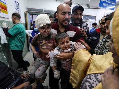 A man carries children injured in Israeli bombardment, at Al Najjar hospital in Rafah in the southern Gaza Strip on March 24, 2024.
