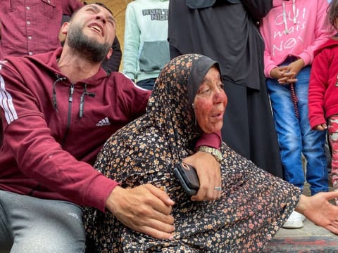 The mother of Palestinian Khalil Abu Shamala, who was killed in an Israeli strike, mourns with her face stained with his blood as Khalil's brother reacts at Al Aqsa hospital in Deir Al Balah in the central Gaza Strip, March 27, 2024.